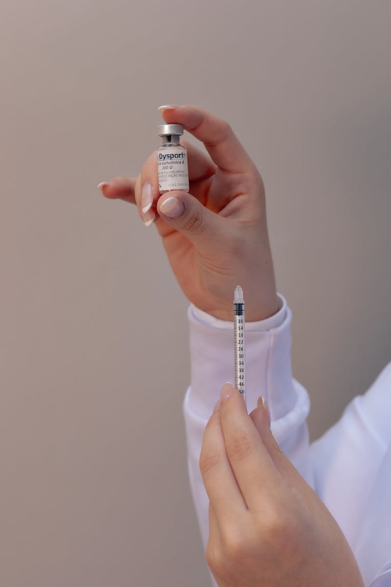 Hands holding a Dysport botox vial and syringe, highlighting cosmetic procedures.